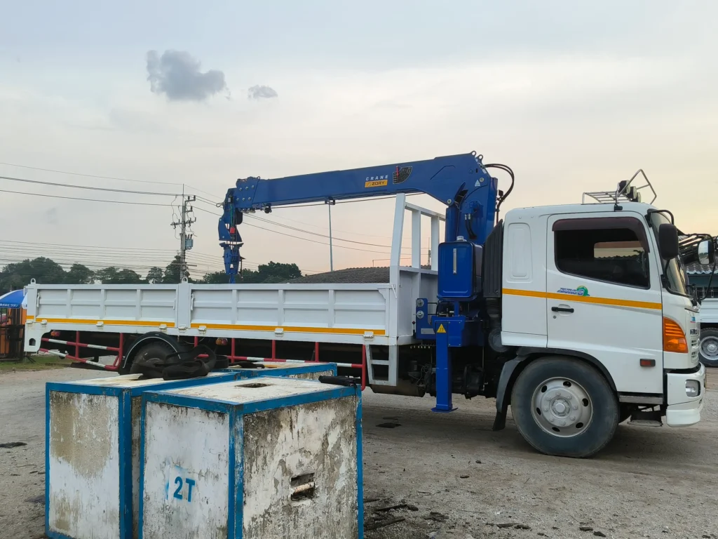 A blue Zory SQS125G-5 5-ton telescopic boom crane is mounted on a white truck. This 5 ton truck mounted crane, a typical lorry mounted crane, shows its telescopic boom structure, parked near 2-ton test weights.