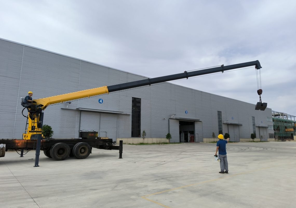 Technicians conducting a critical static/dynamic load test on a 10 ton crane at the factory; this telescopic boom crane, a type of truck mounted crane, is being tested to ensure compliance with standards.